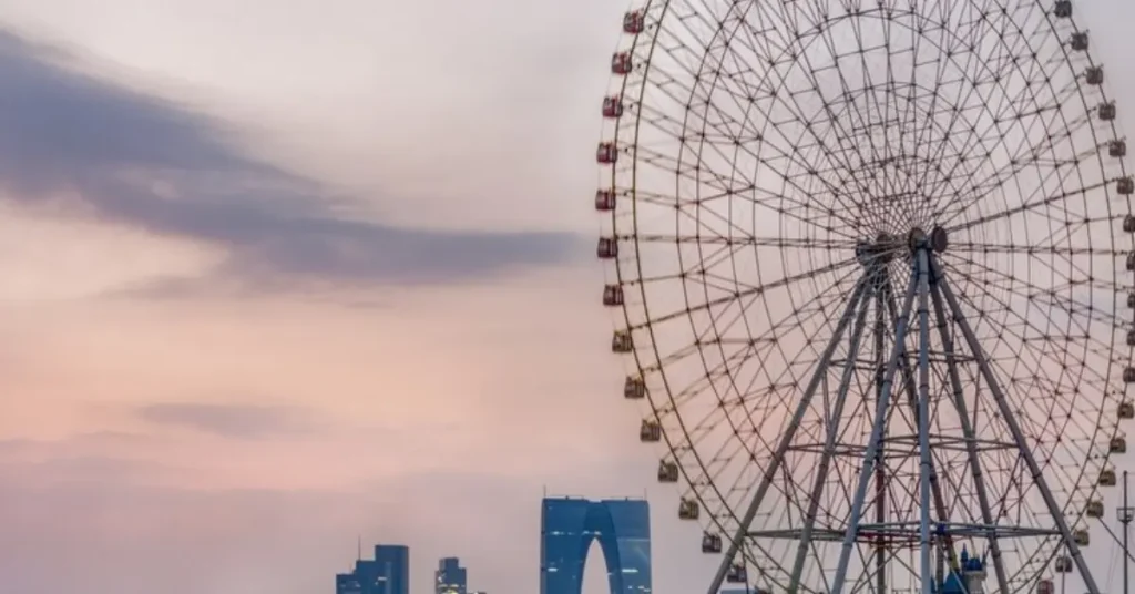 Ferris wheel with a cityscape backdrop, showcasing a skyline of buildings and clear skies.